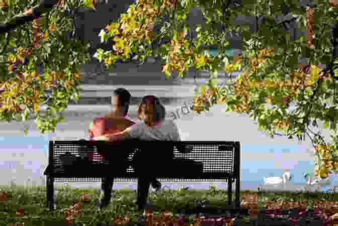 A Young Couple Sitting On A Bench In The Park, Laughing And Holding Hands. They Are Surrounded By Nature. Forgetting You L A Casey